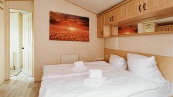 Une chambre d’hôtel avec un lit, un tableau, des armoires en bois et une porte.