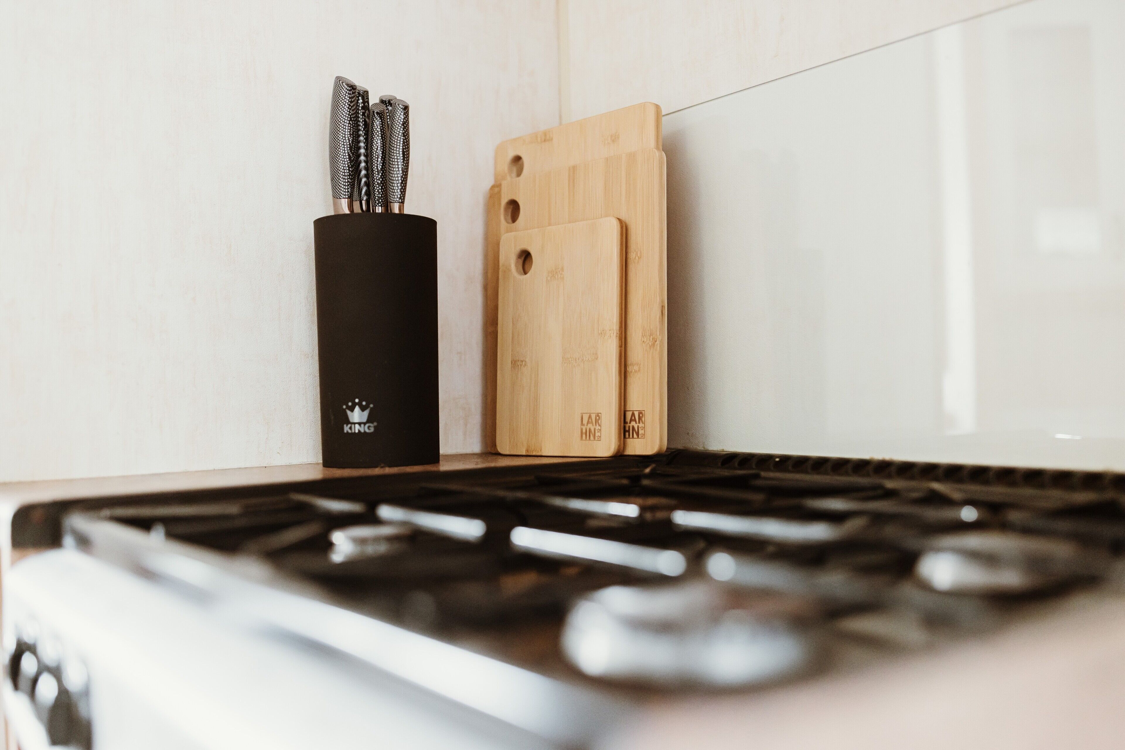 A kitchen with a black knife block, two wooden cutting boards, and a stove.