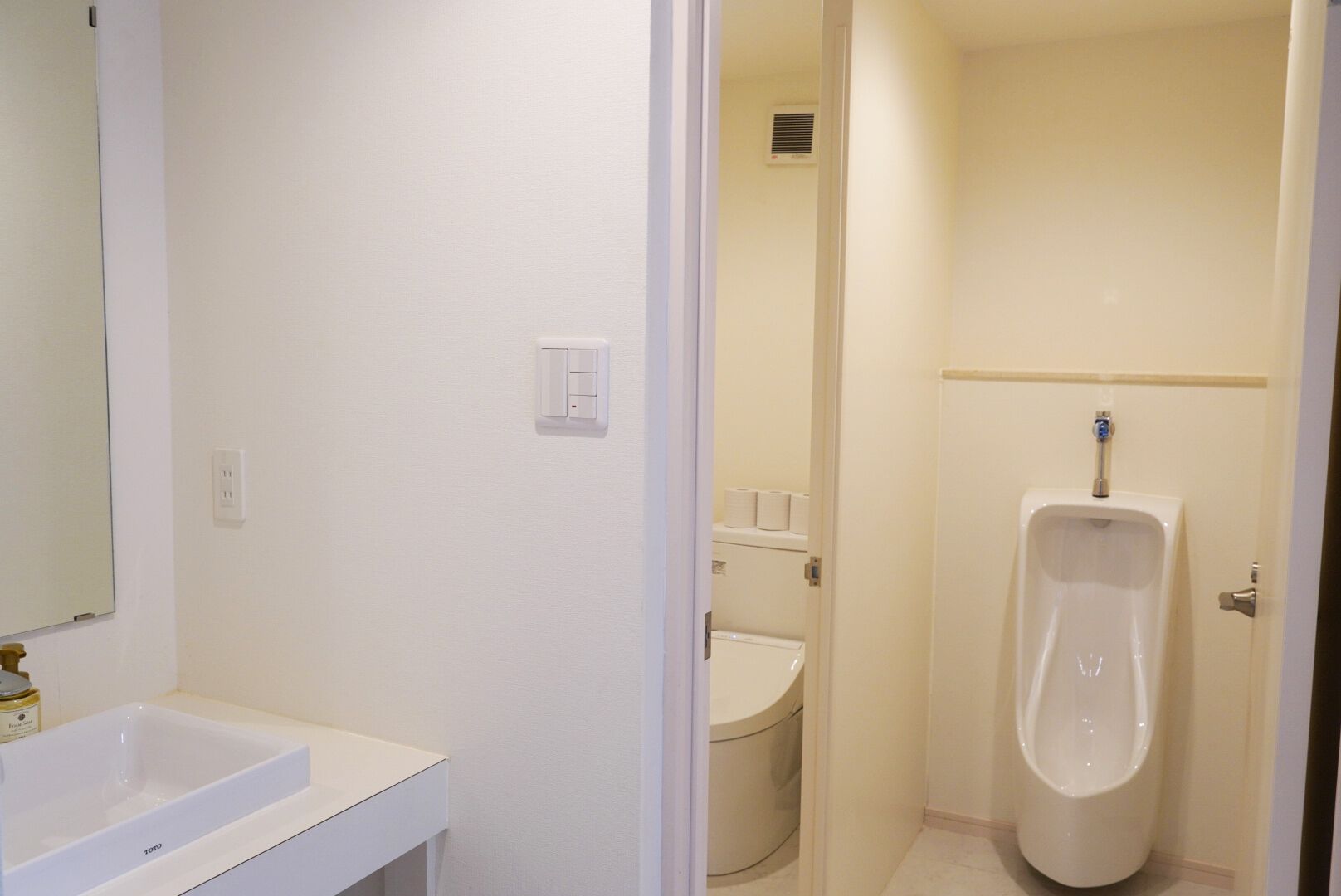 A bathroom with a white sink, toilet, and urinal.