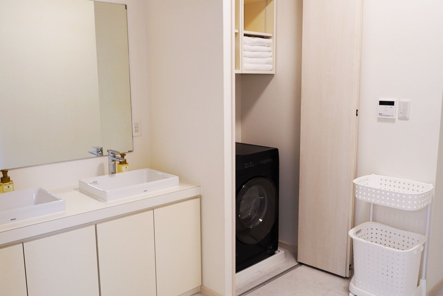 A compact bathroom with a white sink, mirror, and a black washing machine.