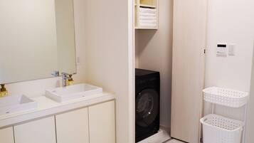 A compact bathroom with a white sink, mirror, and a black washing machine.