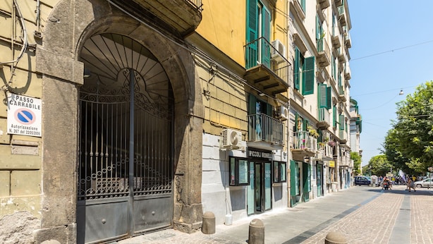 A cobblestone street with historic buildings, a metal gate, and bollards.