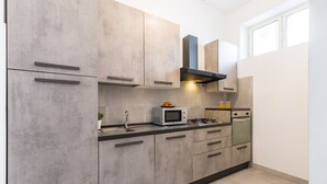 A modern kitchen with grey cabinets, a microwave, a stove, and a sink.