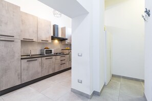 Una cocina moderna con armarios de madera clara, un microondas y una estufa a gas.
