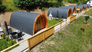 A row of wooden dome-shaped cabins with a paved walkway in between. - Frankenwald Chalets (Wilhelmsthal)