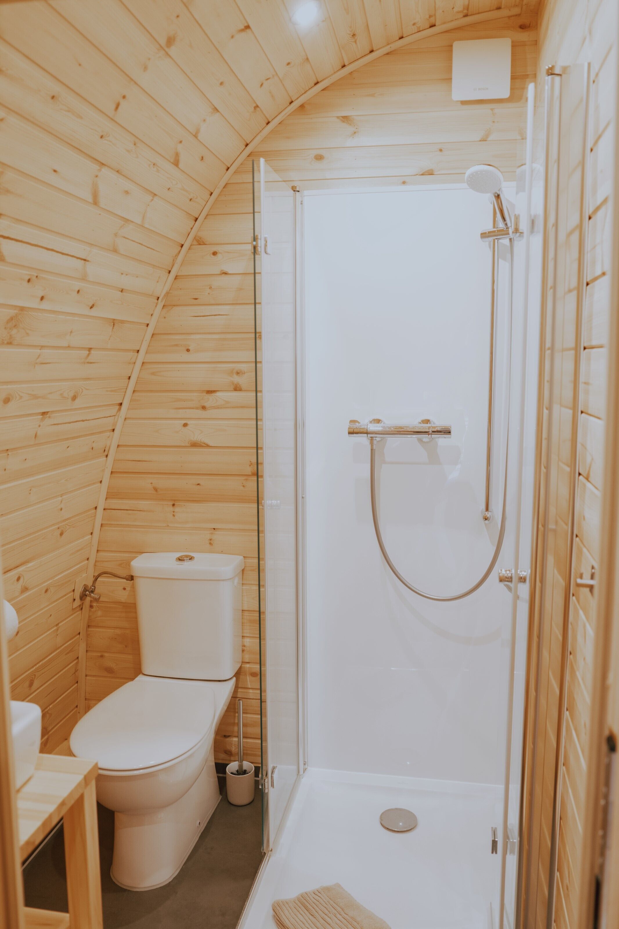Ein kleines Badezimmer mit Holzvertäfelung, einer Toilette, einer Dusche und einem Waschbecken.