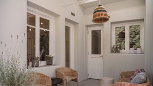 A cozy room with wicker furniture, a small table, and potted plants. - Evas Apartment in the Heart of Chania City (Chania)