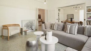 A spacious living room with a grey sofa, white coffee table, and a unique silver vase. - Evas Apartment in the Heart of Chania City (Chania)