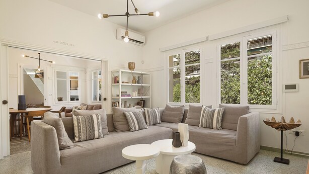 A spacious living room with a sectional sofa, a round coffee table, and a modern chandelier. - Evas Apartment in the Heart of Chania City (Chania)