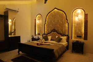 A bedroom with a large bed, a nightstand, a dresser, and a mirror.
