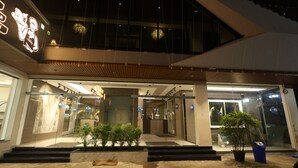 A modern hotel entrance with a glass facade, a wooden overhang, and a potted plant in the foreground. - Govind Palace Restaurant and Resort (Barwah)