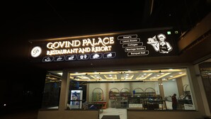 The exterior of Govind Palace Restaurant and Resort with a neon sign listing amenities like Sweet's, Luxury Rooms, Cottages, Marriage Garden, and Banquet Hall. - Govind Palace Restaurant and Resort (Barwah)