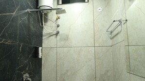 A bathroom with a black marble wall, a white sink, and a shower area. - Govind Palace Restaurant and Resort (Barwah)