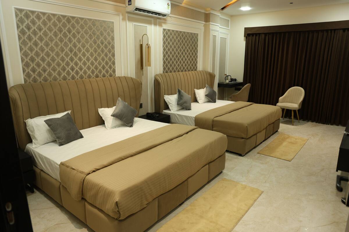 A hotel room with two beds, a desk, and a chair.