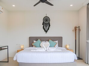 A bedroom with a bed, two bedside tables, a wall-mounted dreamcatcher, and a floor lamp.