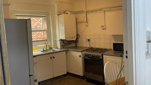 A compact kitchen with white cabinets, a gas stove, a microwave, and a refrigerator.