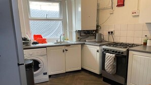 A compact kitchen with a washing machine, a stove, and a sink.