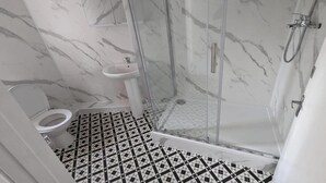 A bathroom with a toilet, sink, and glass-enclosed shower.