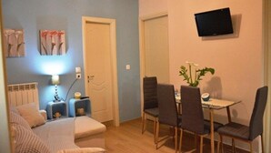 Habitación compacta con cama, mesita de noche, lámpara y una pequeña mesa con sillas.