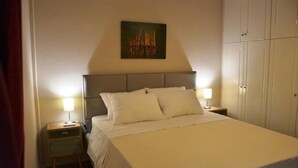 Una cama bien hecha con ropa blanca, un cabecero y dos lámparas de noche.