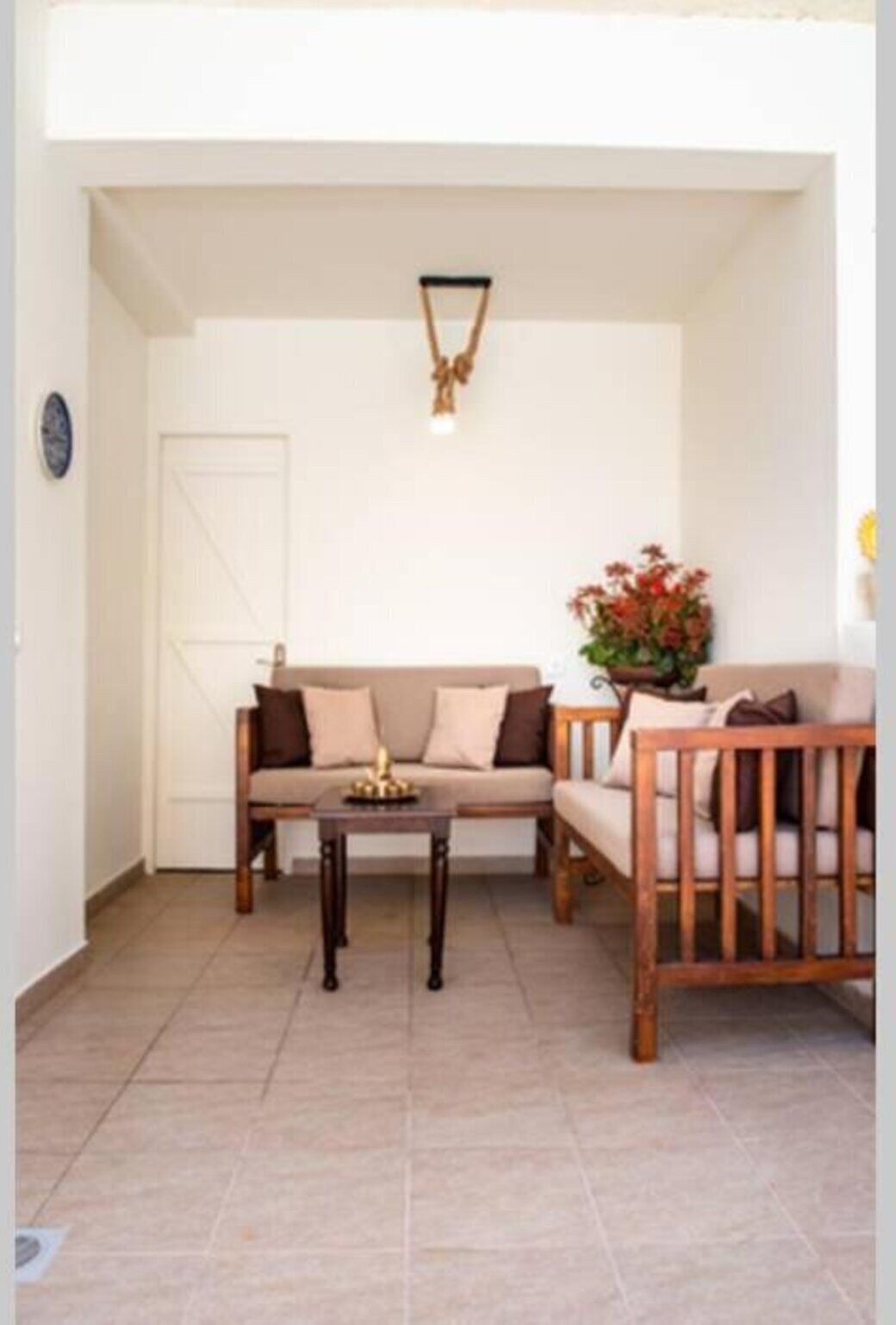 Una sala de estar con un sofá color crema, una silla de madera, una mesita y una planta en maceta.