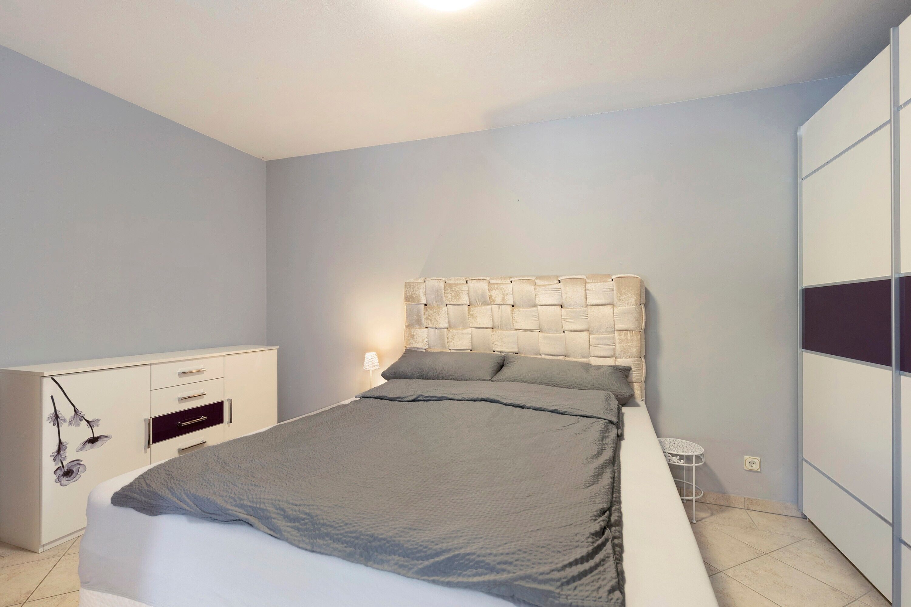 Ein Schlafzimmer mit Bett, Schminktisch, Nachttisch und Kleiderschrank.