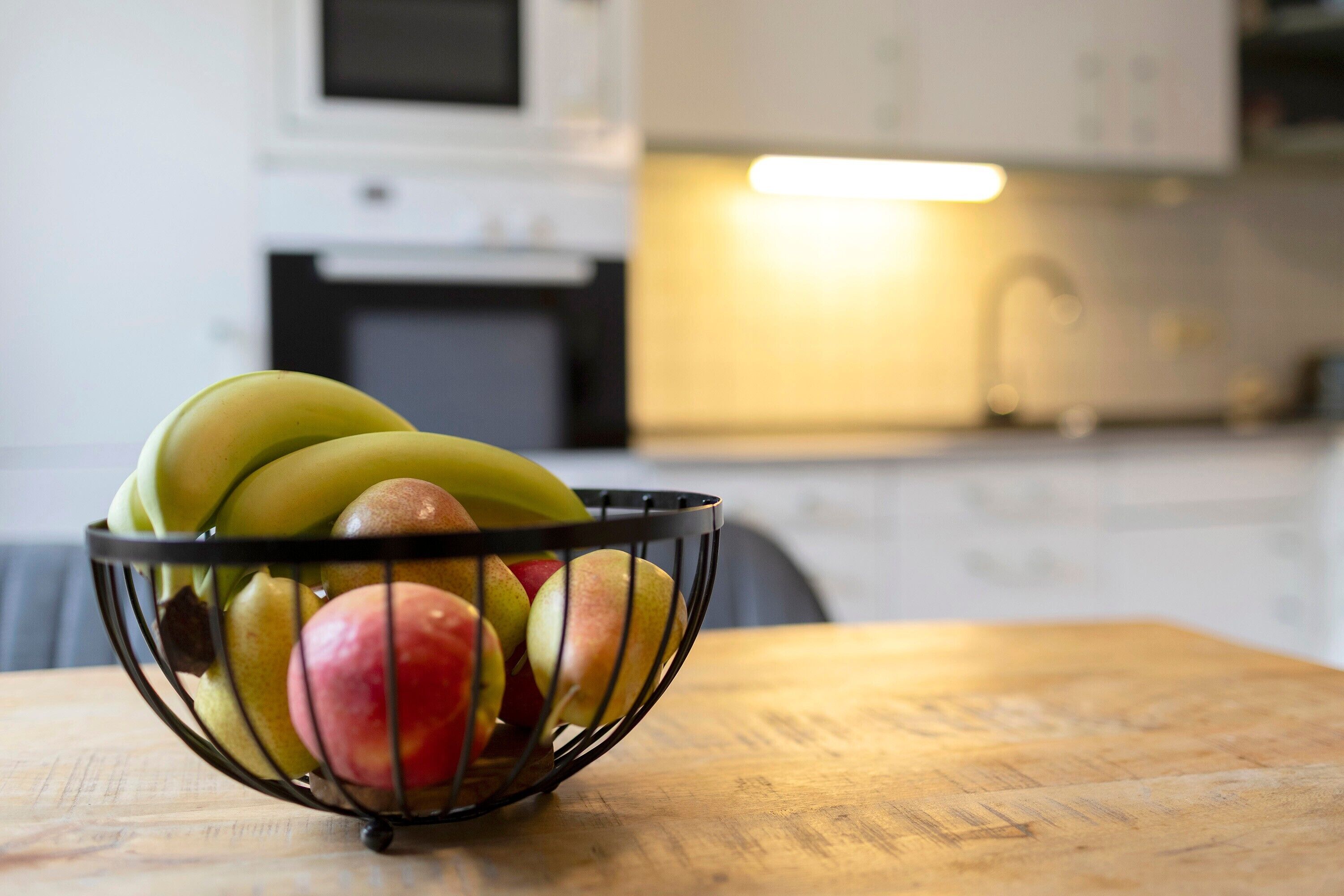 A kitchen with a fruit bowl on a wooden table.