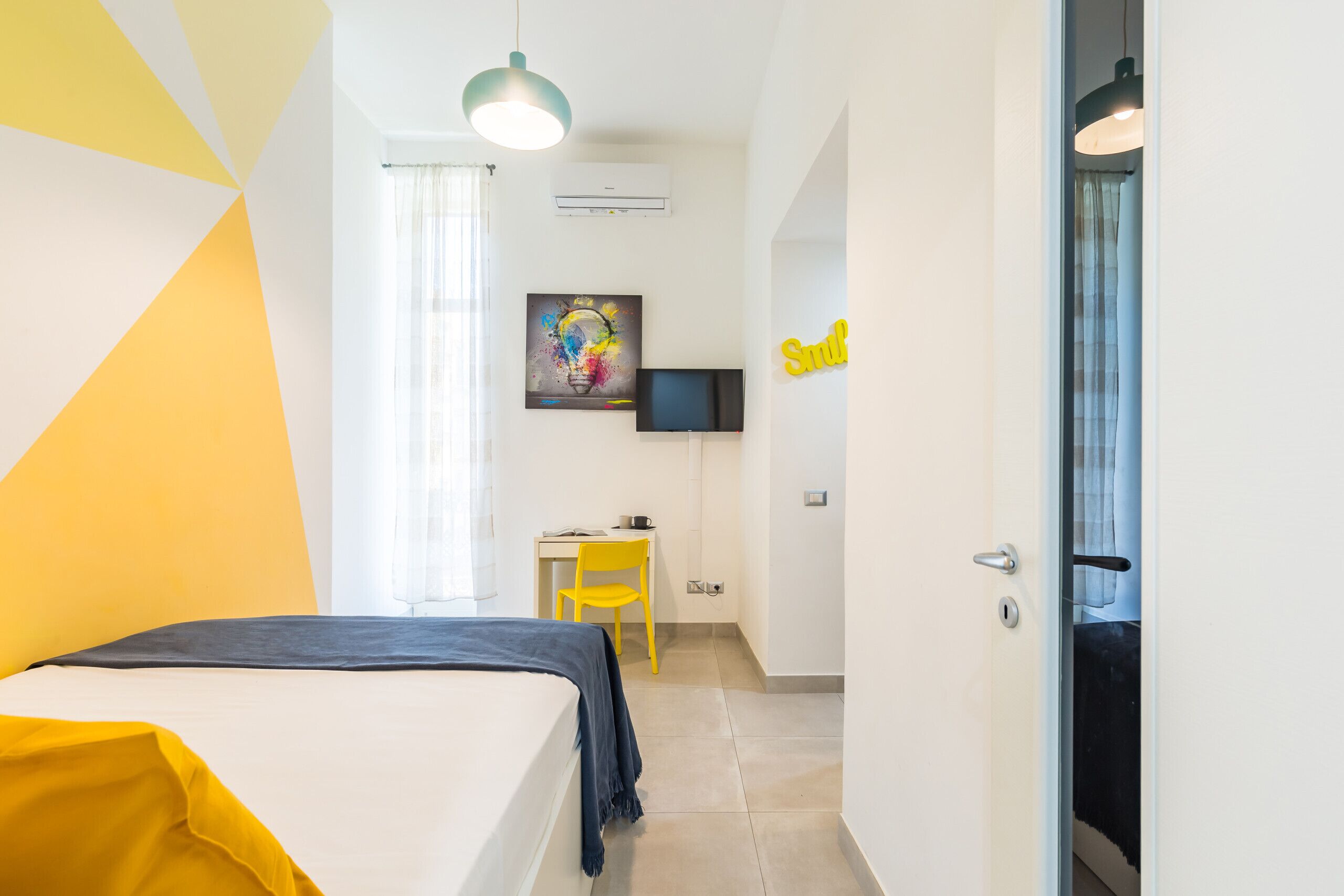 Ein Hotelzimmer mit Bett, Schreibtisch, Stuhl, Fernseher und einer Tür.