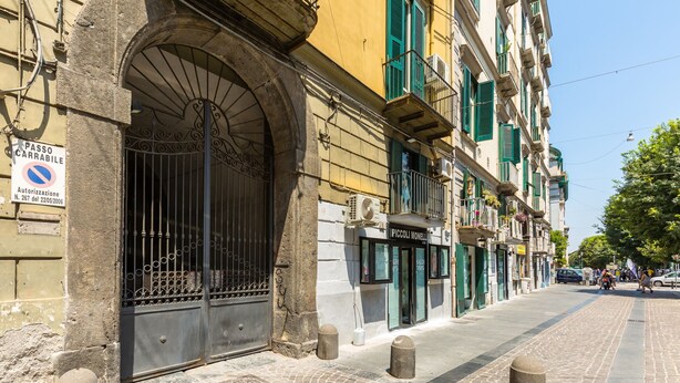 A cobblestone street with historic buildings, a metal gate, and bollards. - Forino Central by Wonderful Italy (Naples)