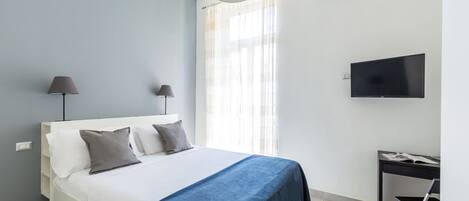 A bedroom with a bed, bedside lamps, a TV, and an air conditioning unit.