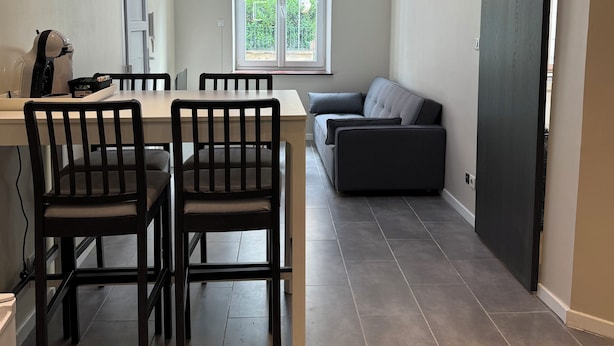 A modern living space with a dining area, a sofa, and a sliding door. - Charmant appartement Nancy centre (Nancy)