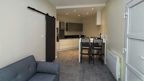A modern apartment with a grey sofa, a white table, and a kitchen in the background. - Charmant appartement Nancy centre (Nancy)