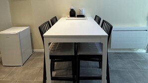 A modern kitchen with a white table, black chairs, a white refrigerator, and a white cabinet. - Charmant appartement Nancy centre (Nancy)