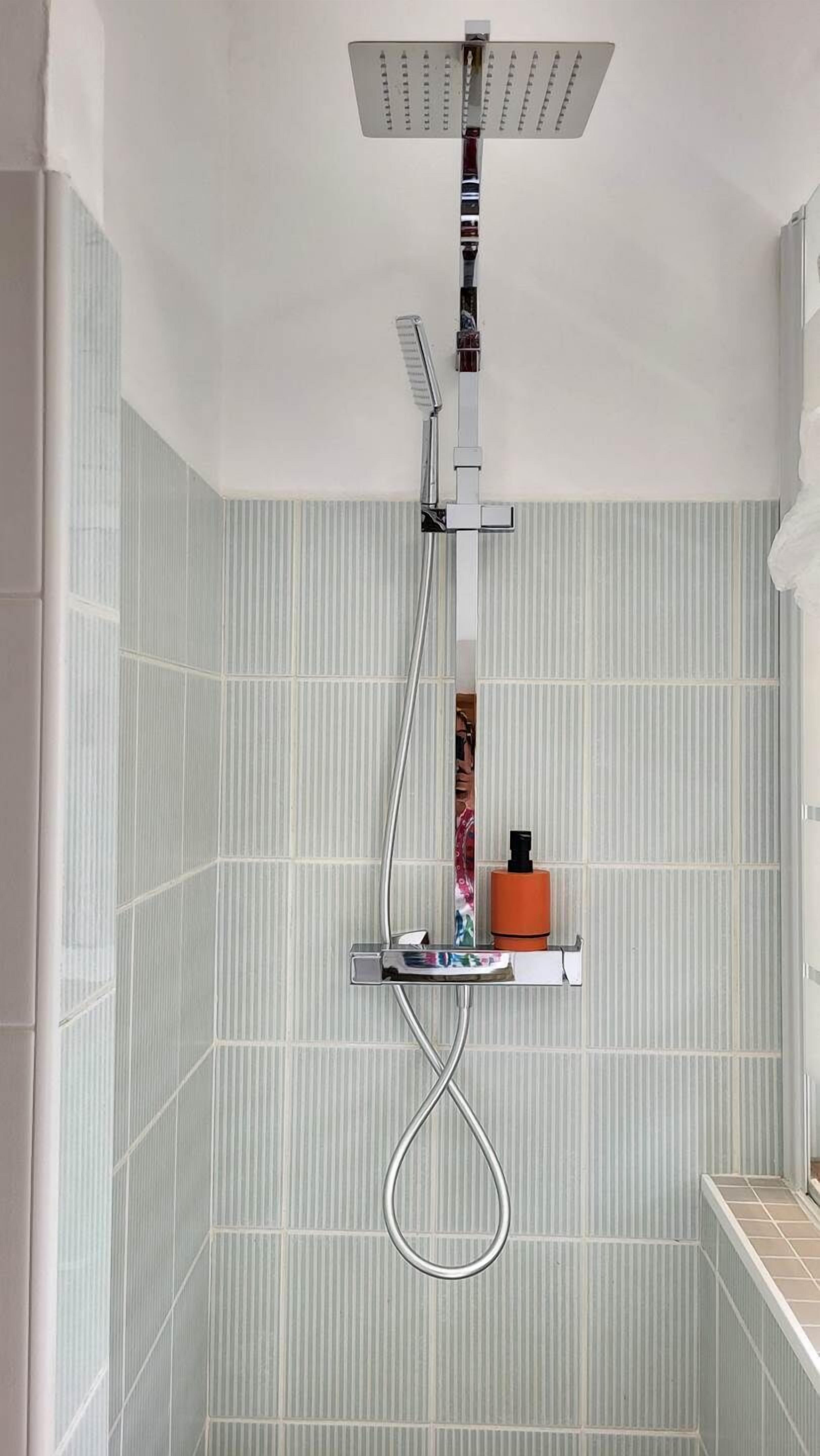 Une douche équipée d’un pommeau de douche à main, d’un autre pommeau de douche à main et d’un troisième pommeau de douche à main.