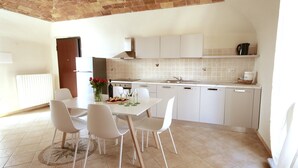 A modern kitchen with white cabinets, a tiled backsplash, and a dining area with a white table and chairs. - Private historic house for groups with terrace 24 guests 6 apartments Monferrato (Viarigi)