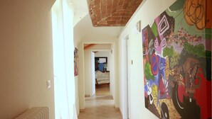 A hallway with a radiator, a chair, and a colorful mural on the wall. - Private historic house for groups with terrace 24 guests 6 apartments Monferrato (Viarigi)