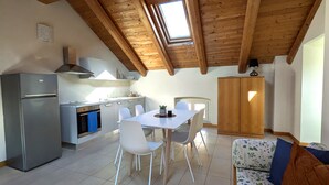 A modern kitchen with a built-in oven, a refrigerator, and a dining area with a table and chairs. - Private historic house for groups with terrace 24 guests 6 apartments Monferrato (Viarigi)
