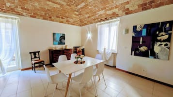 Un coin repas avec une table et des chaises blanches, un meuble en bois et un tableau accroché au mur.