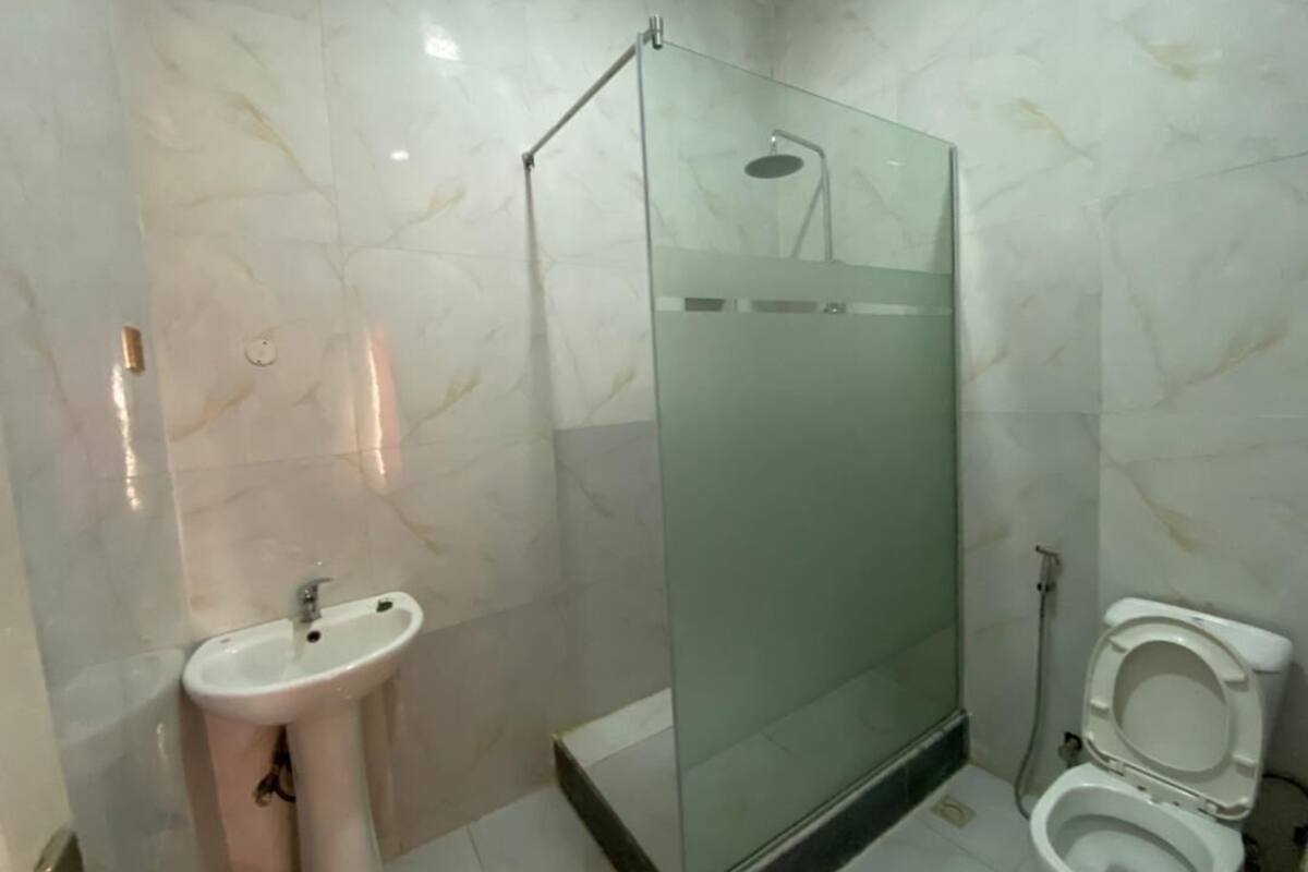 A bathroom with a glass-enclosed shower, a pedestal sink, and a toilet.
