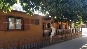 Une maison en bois avec une cour clôturée, un arbre et un ciel dégagé.
