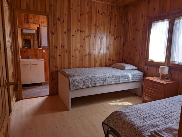 A wooden-paneled room with a bed, a nightstand, a dresser, and a mirror.