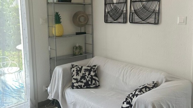 A room with a white sofa, a metal shelving unit, and three wall-mounted decorative items. - Charming house in Bale -Leymen - Your perfect home for your pets (Leymen)