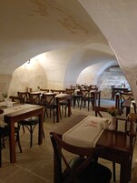 Un comedor con varias mesas y sillas, dispuestas en un diseño semicircular bajo un techo abovedado.