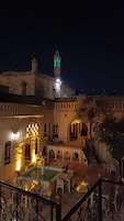 Un patio con piscina, mobiliario exterior y un edificio con un minarete.