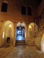 Una escalera de piedra que conduce a un comedor con arcos e iluminación en la pared.