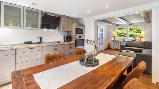A modern kitchen with a dining table, chairs, and a decorative deer statue. - Apartment 'Bödefeld' with Shared Terrace, Private Garden and Wi-Fi (Schmallenberg)