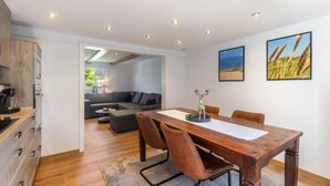 A modern kitchen with wooden cabinets and a dining area with a wooden table and chairs. - Apartment 'Bödefeld' with Shared Terrace, Private Garden and Wi-Fi (Schmallenberg)