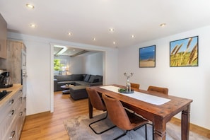 Una cocina moderna con armarios de madera y un comedor con mesa y sillas de madera.