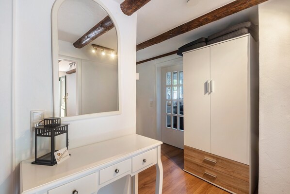 A room with a white dresser, a mirror, a wooden cabinet, and a door leading to another room. - Apartment 'Bödefeld' with Shared Terrace, Private Garden and Wi-Fi (Schmallenberg)