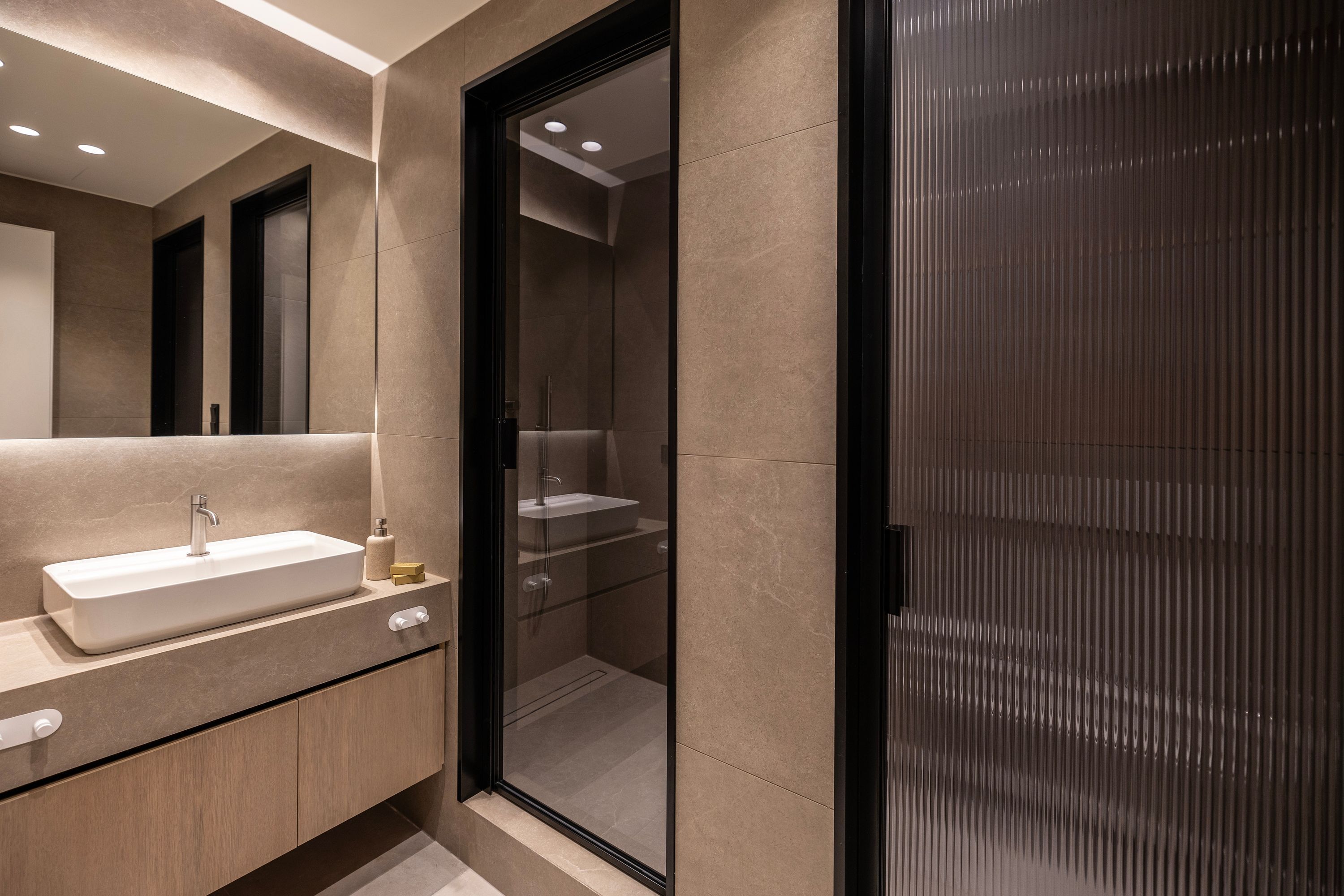 A modern bathroom with a large mirror, a rectangular sink, and a glass shower enclosure.